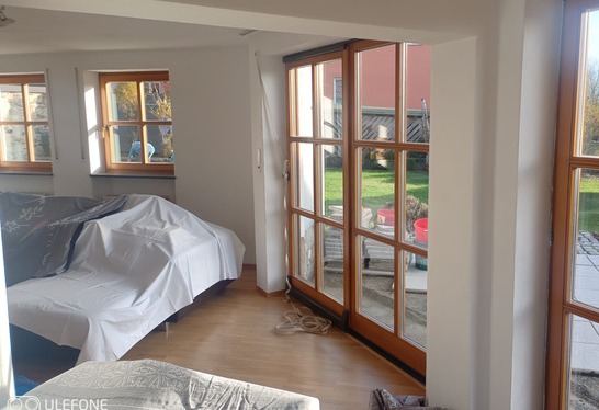 Wohnzimmer beim Fenstertausch: Sofa mit Folie abgedeckt, neue Fenstertüren bereits eingebaut